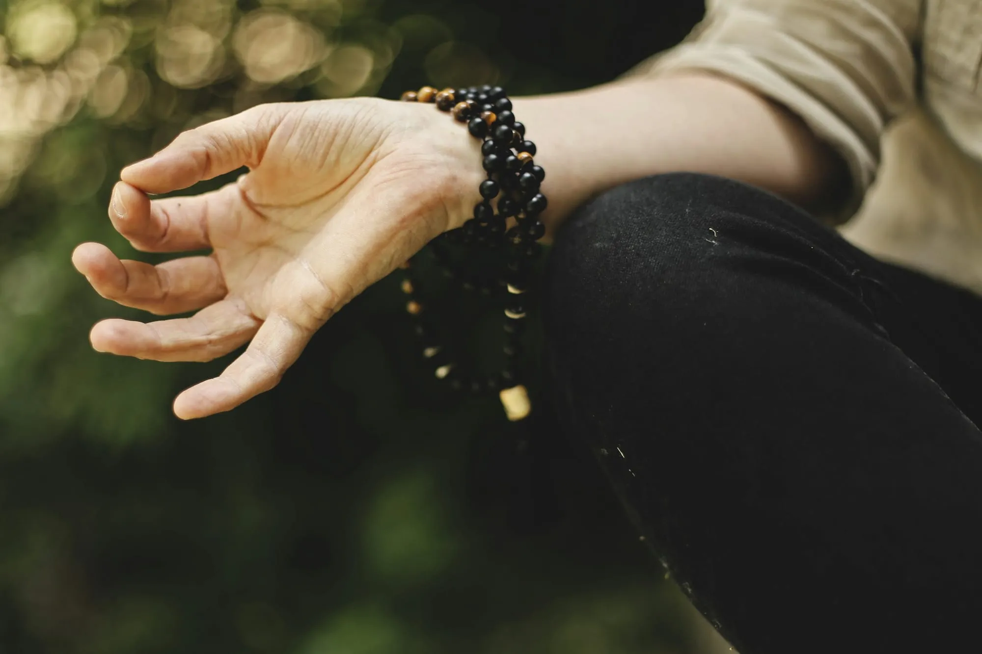 Hand in Meditationshaltung vor grünem Hintergrund
